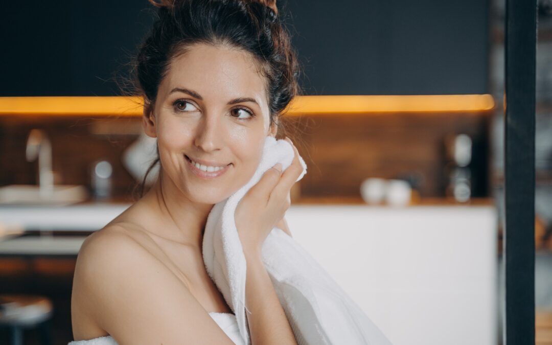 Smiling hispanic girl wiping face by towel enjoy fresh glowing skin after skincare treatment at home